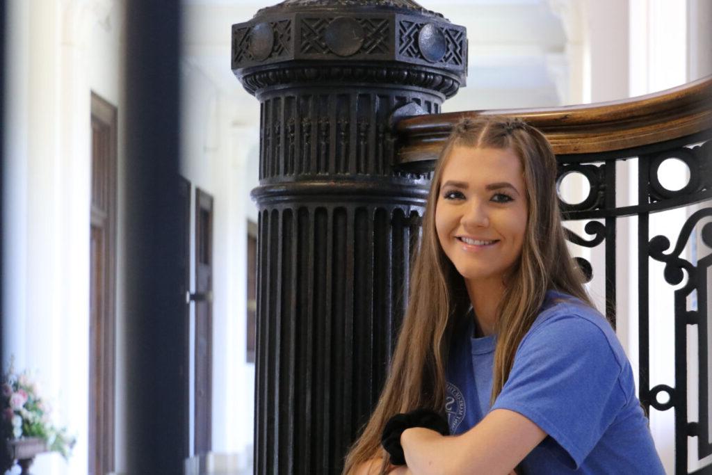 Smiling student sitting on the Le Fer staircase